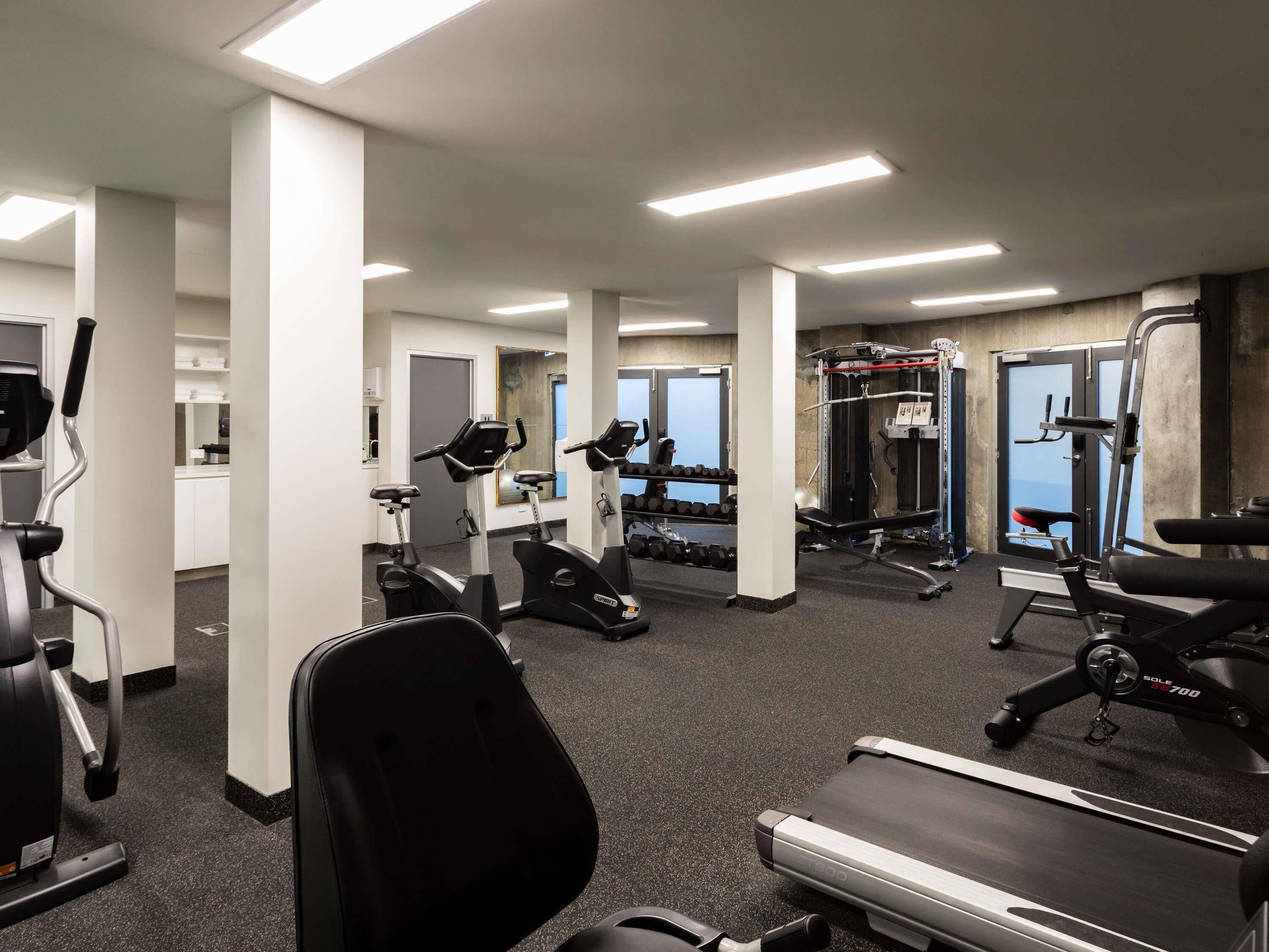 Une salle de sport équipée de tapis de course, de vélos elliptiques et de matériel de musculation.