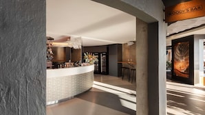 A bar area with a sign reading 'WOODY'S BAR,' a counter with various items, and a large framed artwork on the wall. - Peppers Silo Launceston (Invermay)
