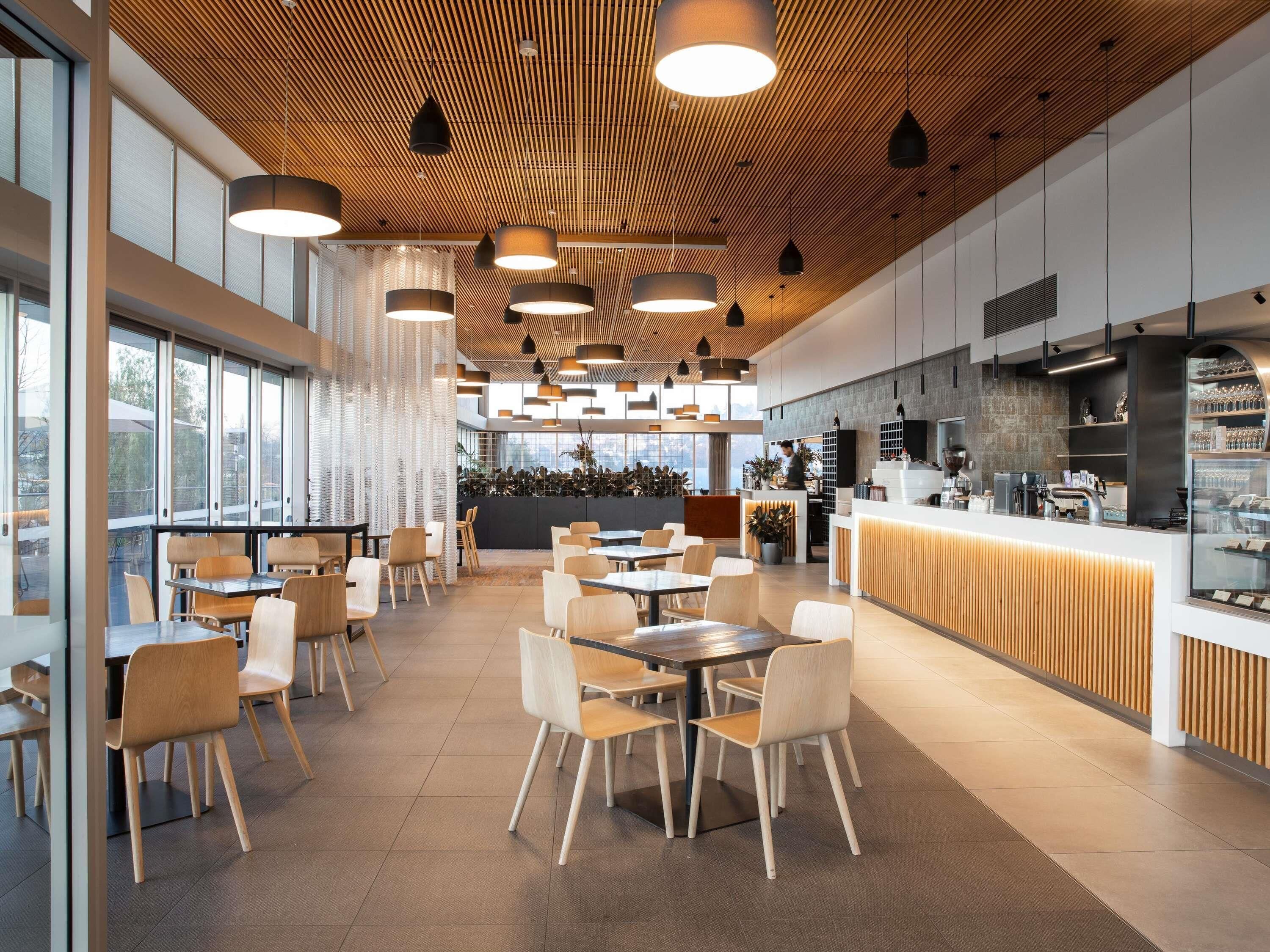 A modern cafe with wooden ceiling, large windows, and a counter with a display of items.