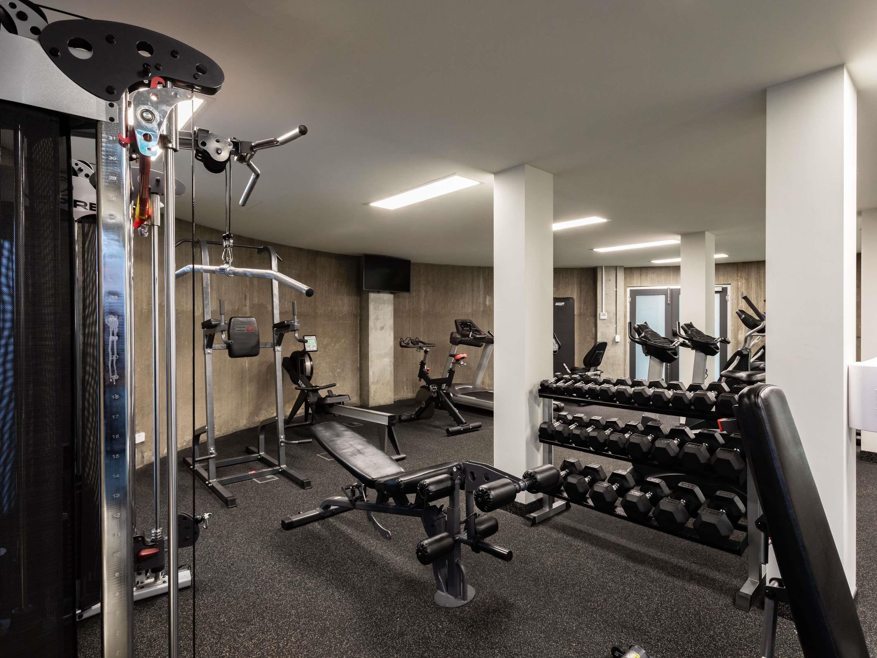 Un gimnasio con equipo de ejercicio, cintas de correr y mancuernas.