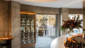 A modern bar area with wine bottles, a glass display case, and a view of the outdoors. - Peppers Silo Launceston (Invermay)