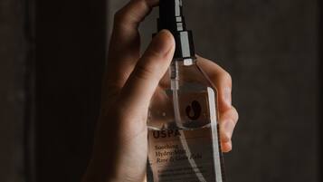 A hand holding a bottle of USPA Soothing Hydro-Mist Rose & Gutu Kola.