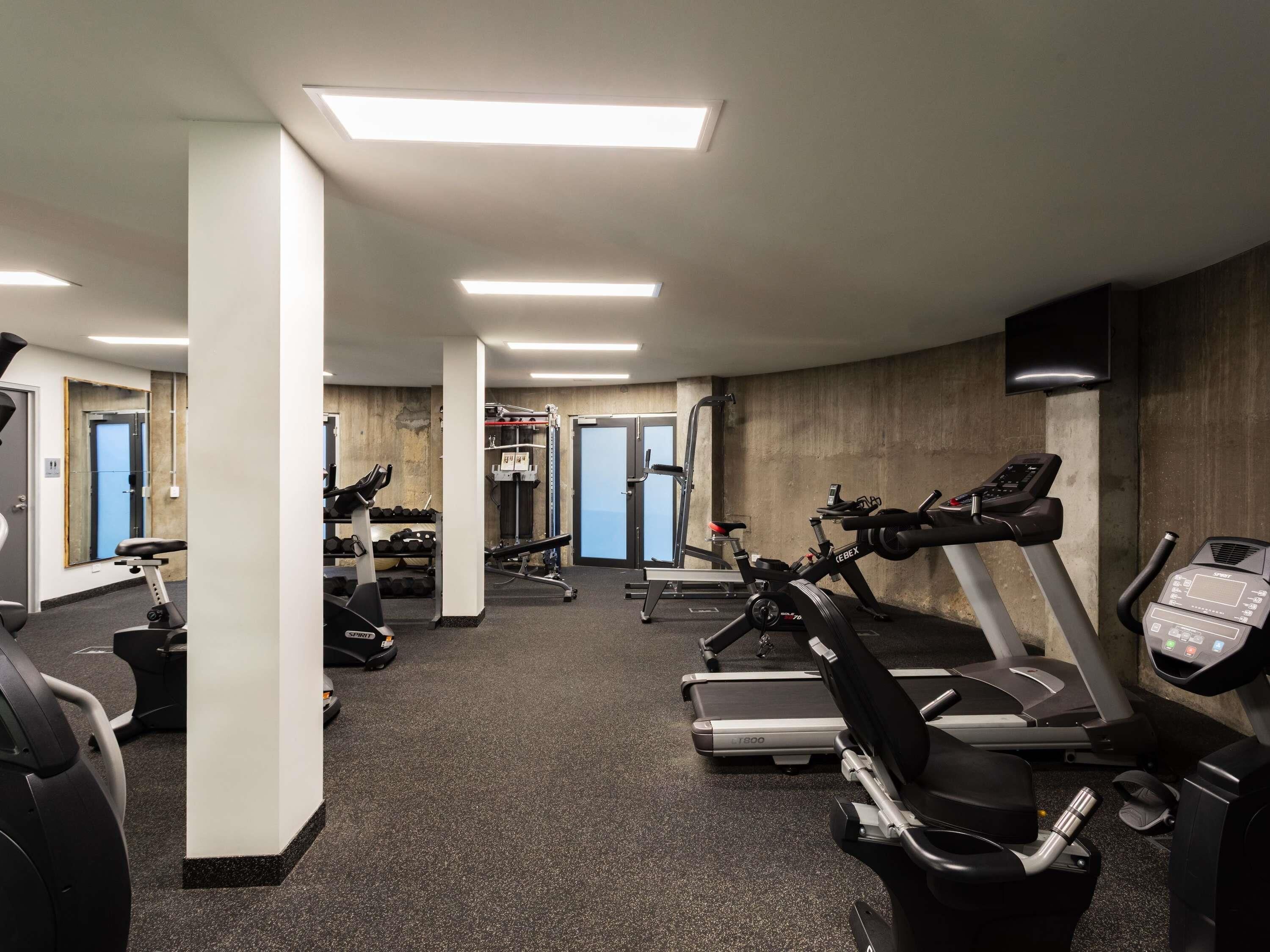 Ginásio com esteiras, elípticos e equipamentos de musculação.