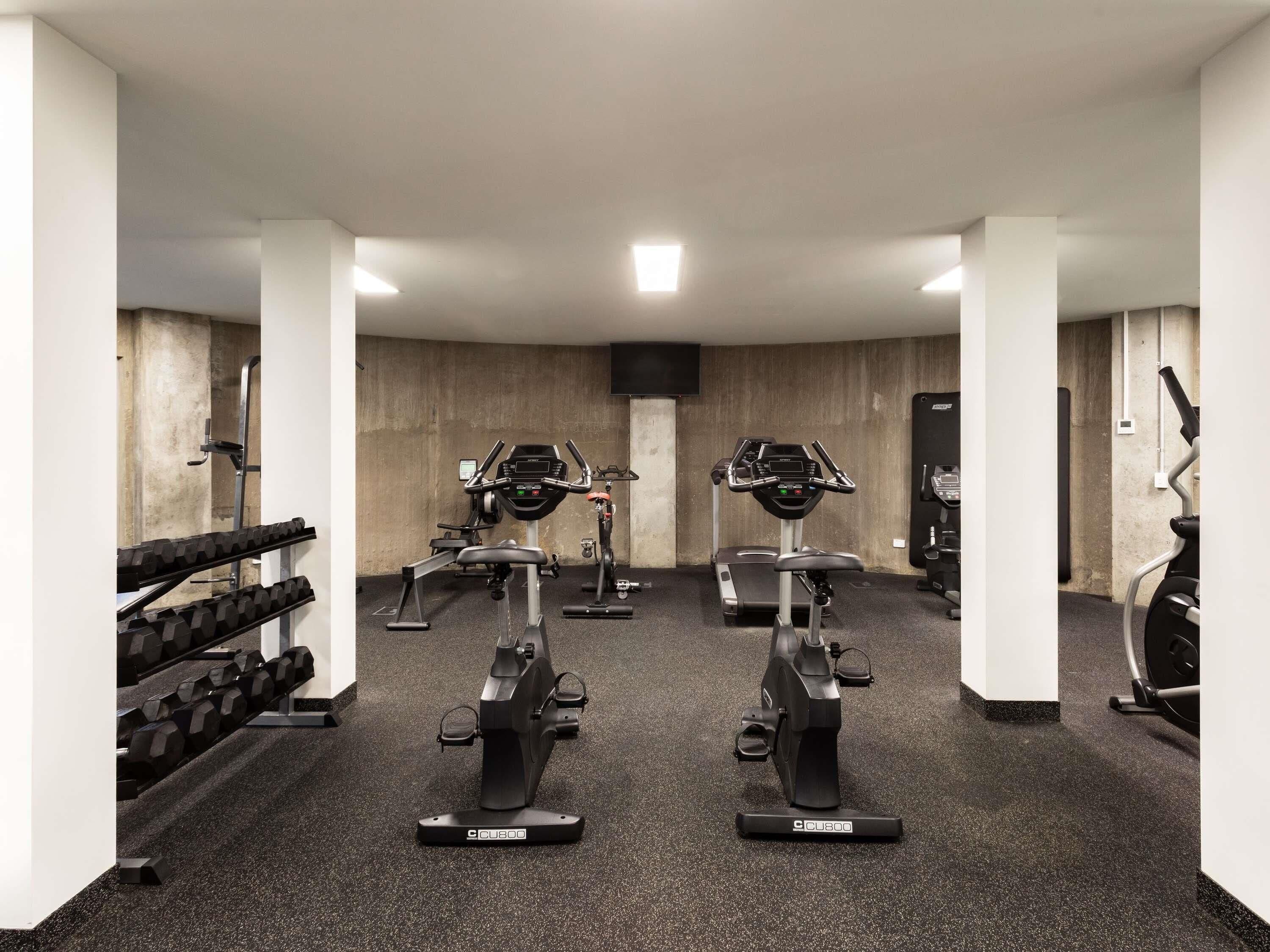 A gym with treadmills, weight machines, and dumbbells.