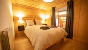 Un dormitorio con paneles de madera, una cama, dos lámparas de noche y un radiador.