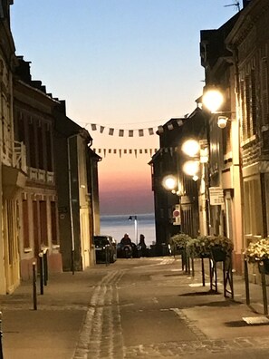En gata med byggnader på båda sidor, en klar himmel och en solnedgång i fjärran.