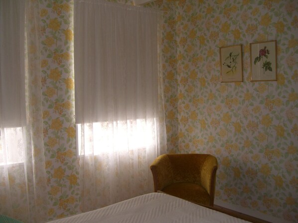 A room with floral wallpaper, a bed, a chair, and two framed pictures on the wall. - Charming house in YPORT 300 meters seaside sun terrace gardens (Yport)