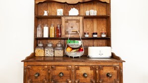 Un meuble en bois contenant des bocaux en verre, un panier de fruits et un grille-pain.