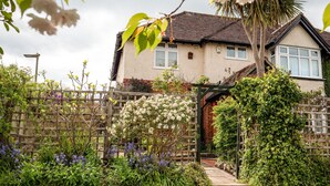Une maison avec un jardin, une clôture en bois et un chemin menant à l’entrée.