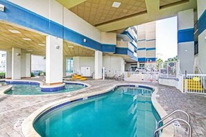 An indoor swimming pool with multiple lanes, a changing room area, and a covered seating area.