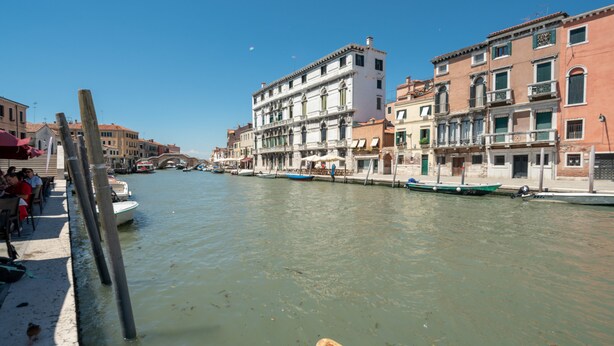A canal with boats, buildings, and a bridge. - Ca' degli Archi 2 (Venice)
