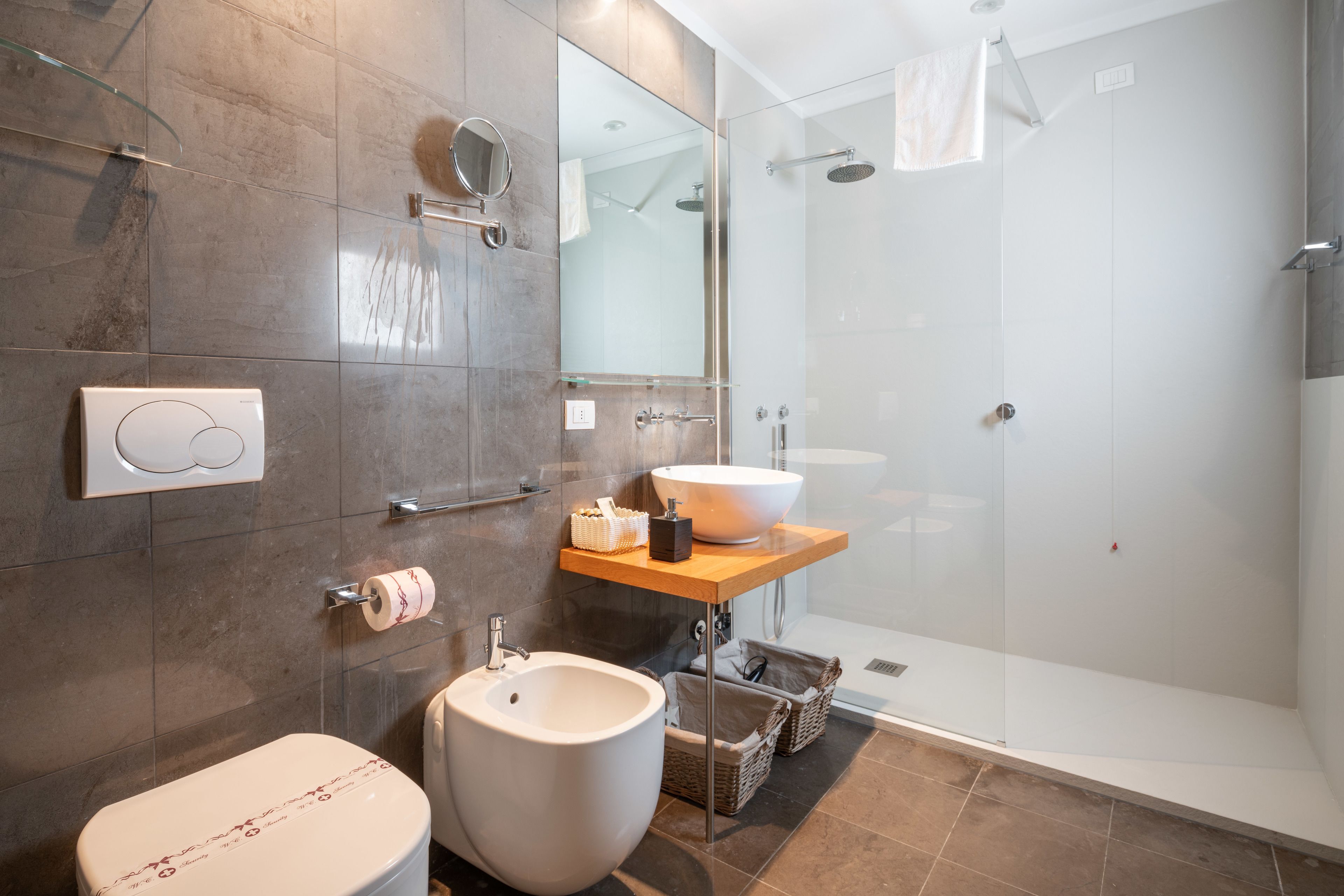 Une salle de bain moderne dotée de toilettes spacieuses, d’un bidet et d’une douche à parois de verre.