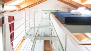 A dormitory-style room with a bunk bed, a glass railing, and a small kitchenette. - Ca' degli Archi 2 (Venice)