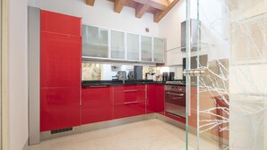 A modern kitchen with red cabinets, a black countertop, and stainless steel appliances. - Ca' degli Archi 2 (Venice)