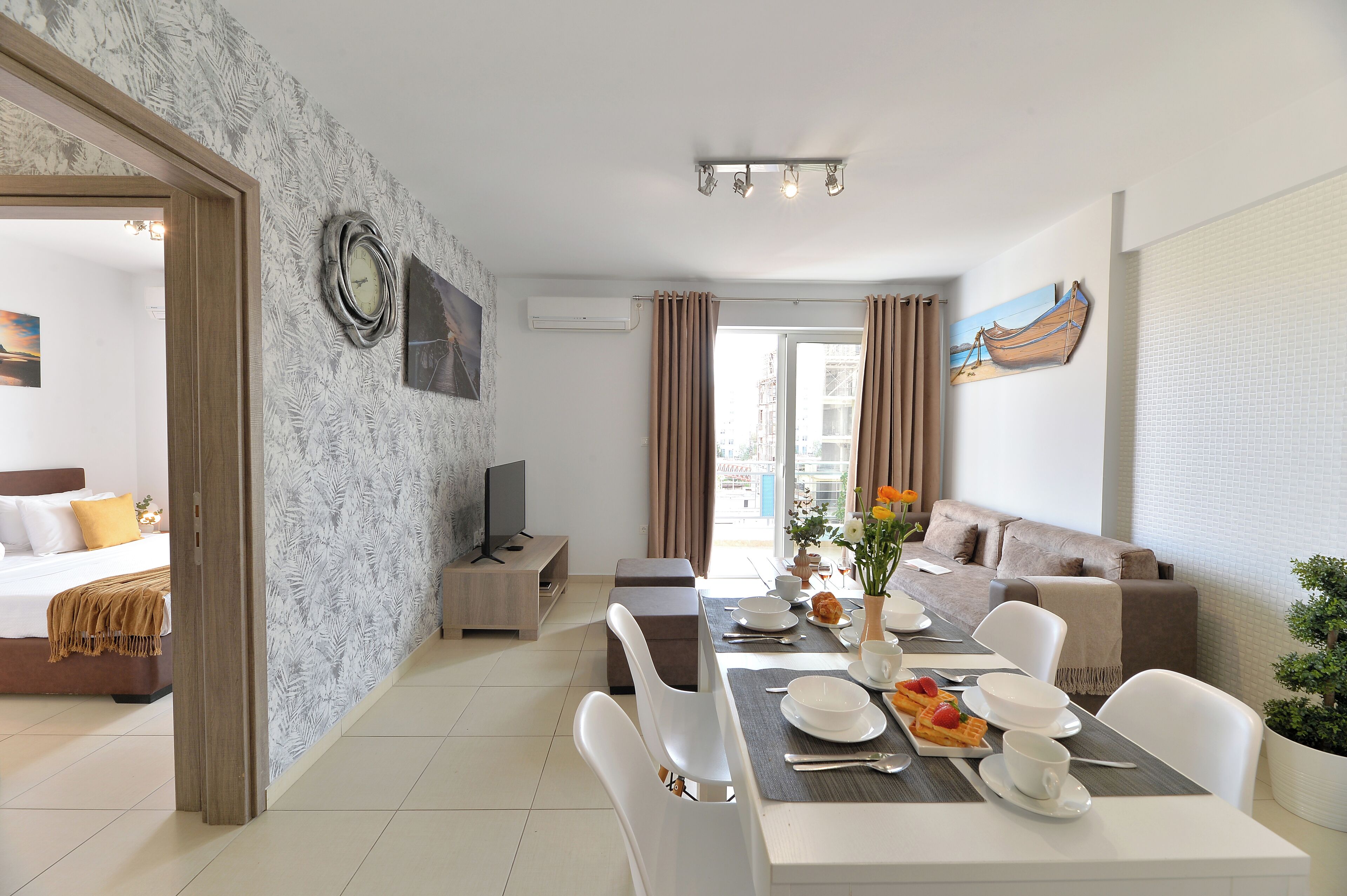 A modern living room with a dining area, a sofa, a TV, and a balcony with curtains.