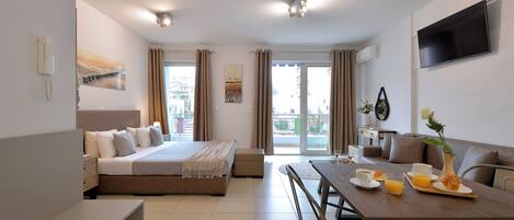 Une chambre d’hôtel moderne équipée d’un lit, d’un coin repas et d’une télévision.