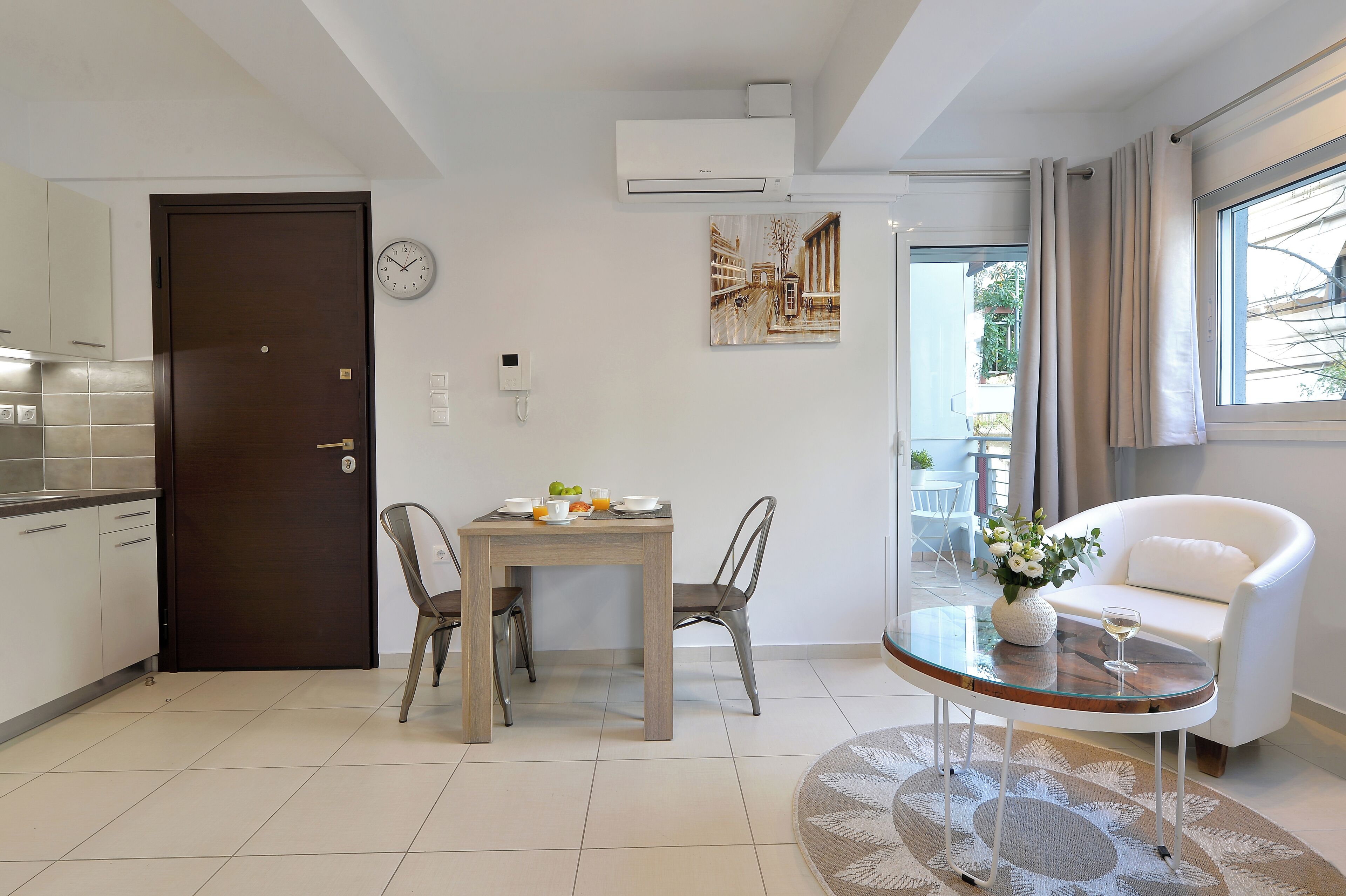 A modern kitchen with a dining area, a white sofa, and a window with curtains.