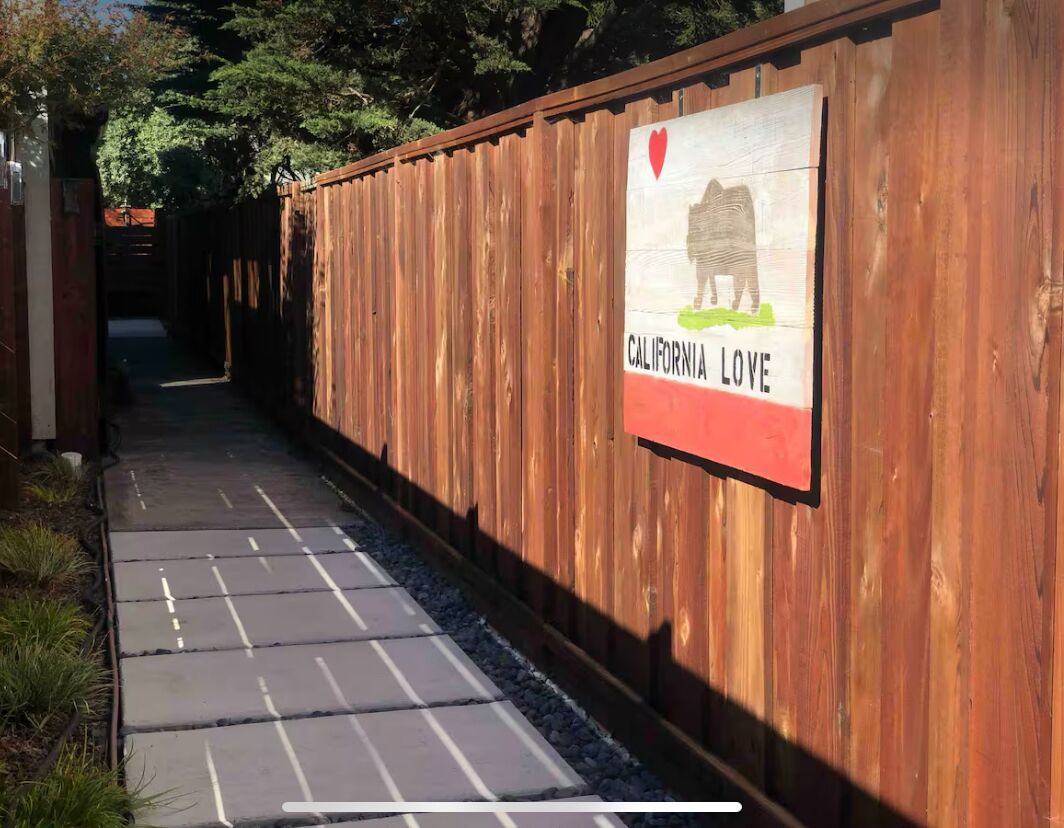 Une clôture en bois sur laquelle est affiché un panneau indiquant « CALIFORNIA LOVE » et un symbole en forme de cœur.