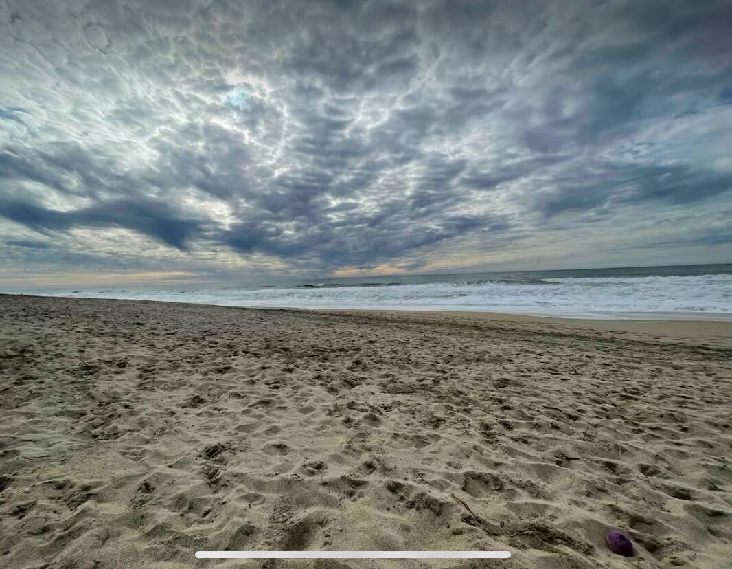 Une plage avec une vaste étendue de sable et un ciel nuageux.