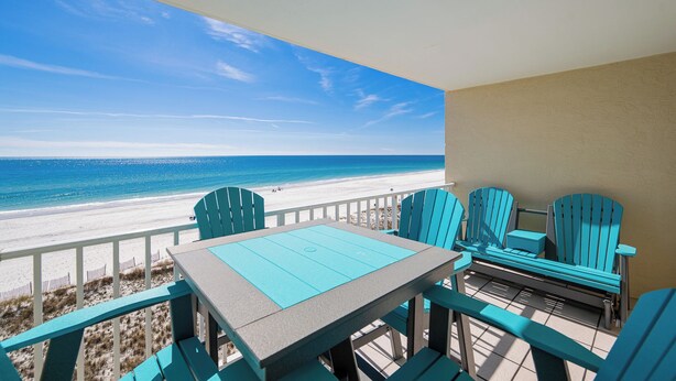 A balcony with a table and chairs overlooking a beach.