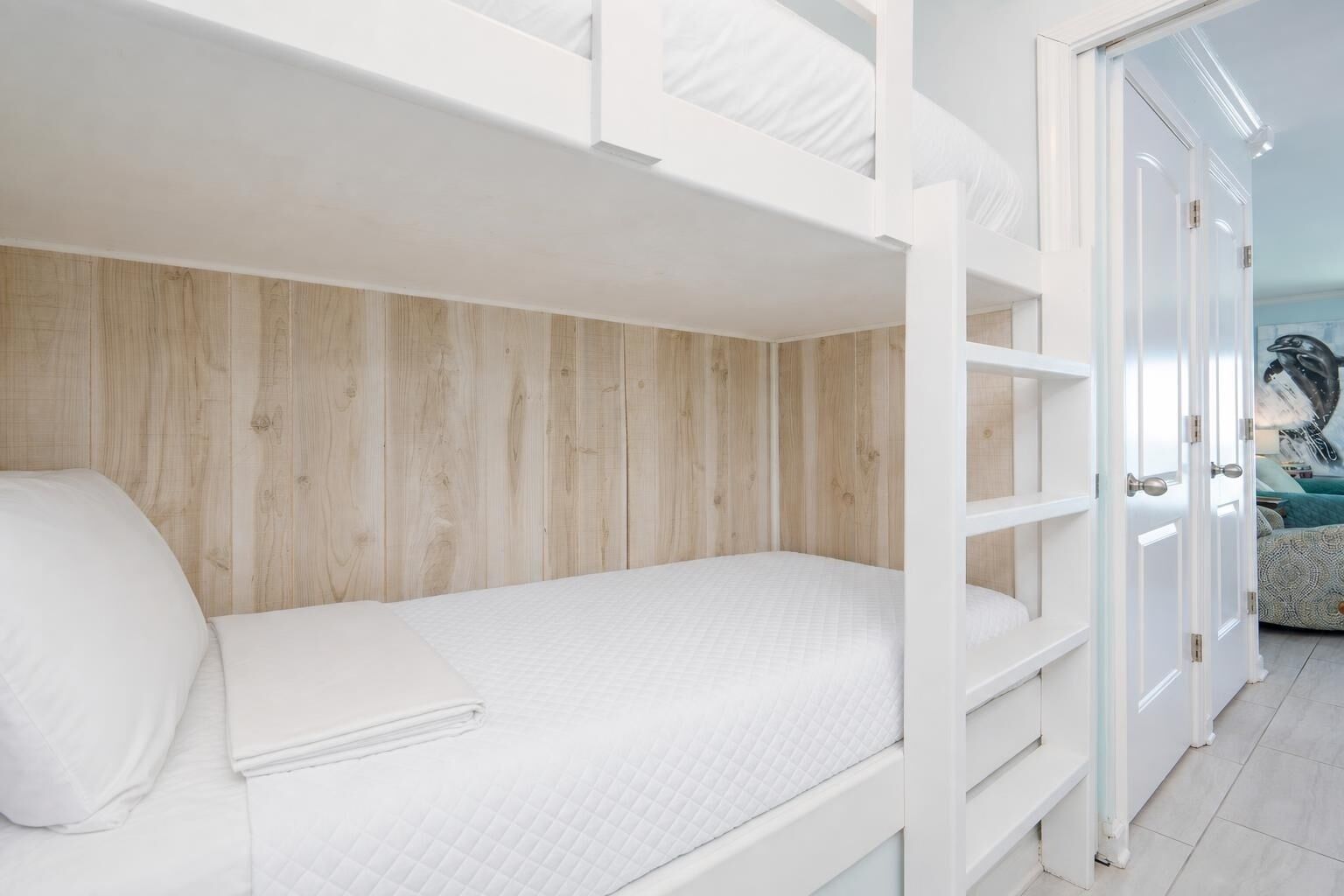 Una cama litera con colchón blanco y pared de madera al fondo.