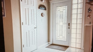 A white door with a decorative plate, a small window with bars, and a doormat.