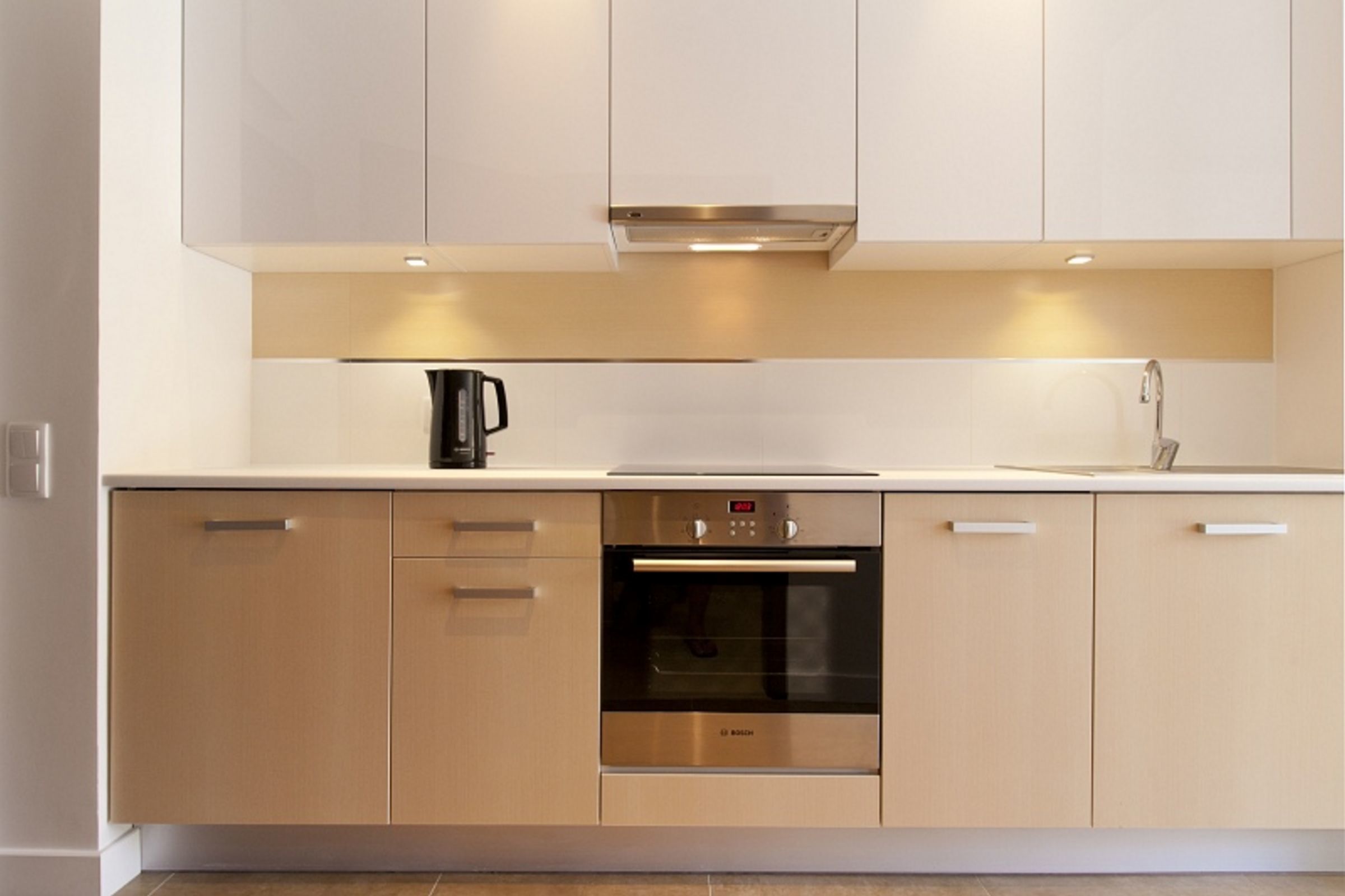 A modern kitchen with a Bosch oven, light-colored cabinets, and a coffee maker.