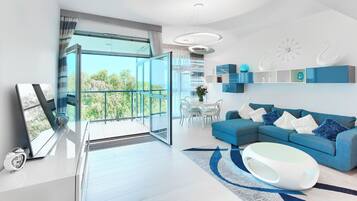 Un salon moderne avec un canapé bleu, une table basse blanche et un coin repas comprenant une table et des chaises blanches.