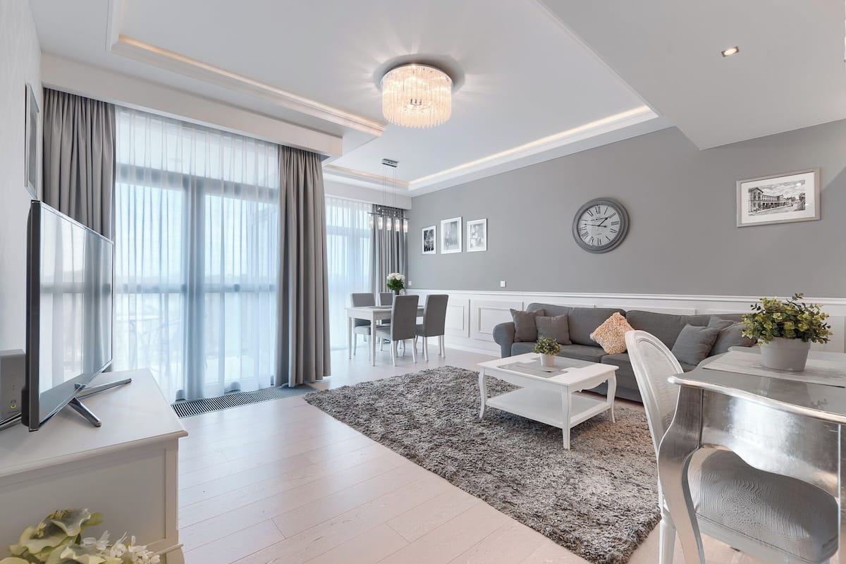 Un salon moderne avec un téléviseur à écran plat, une table basse blanche et un canapé gris.