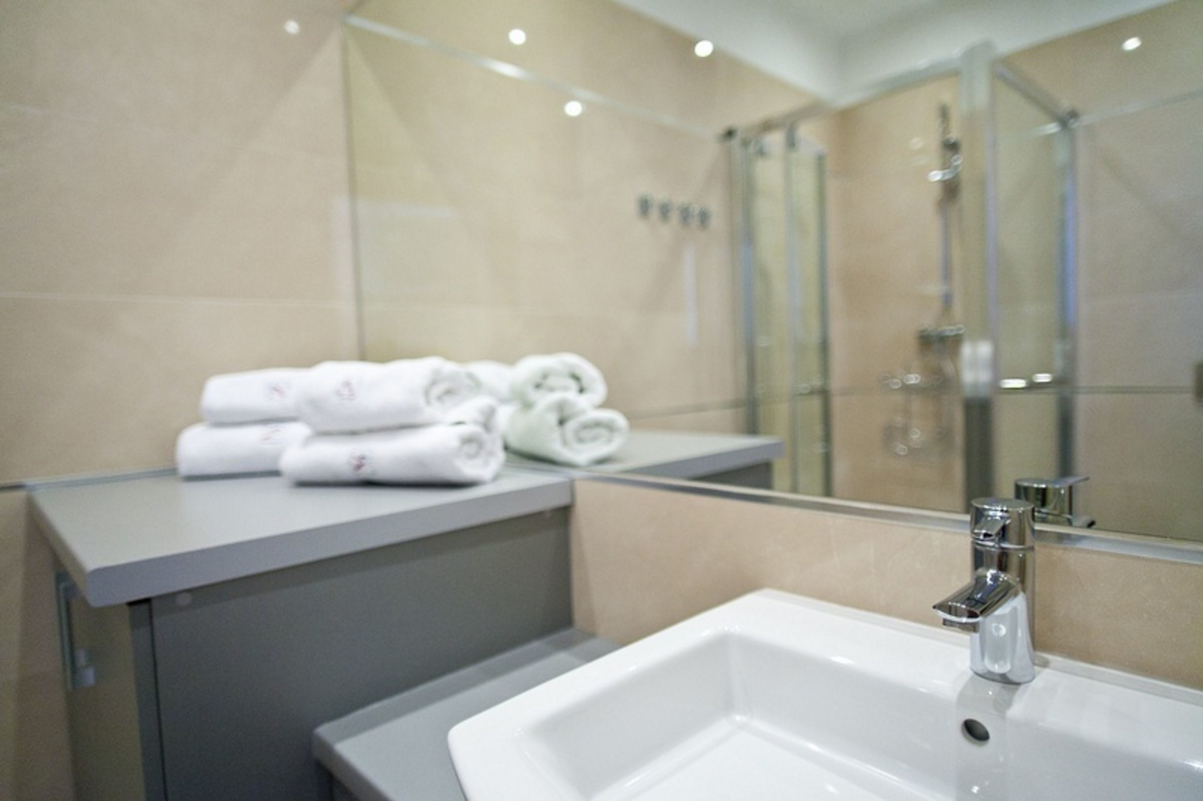 Une salle de bain moderne avec un grand miroir, un lavabo et une douche à parois de verre.