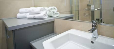 Une salle de bain moderne avec un grand miroir, un lavabo et une douche à parois de verre.