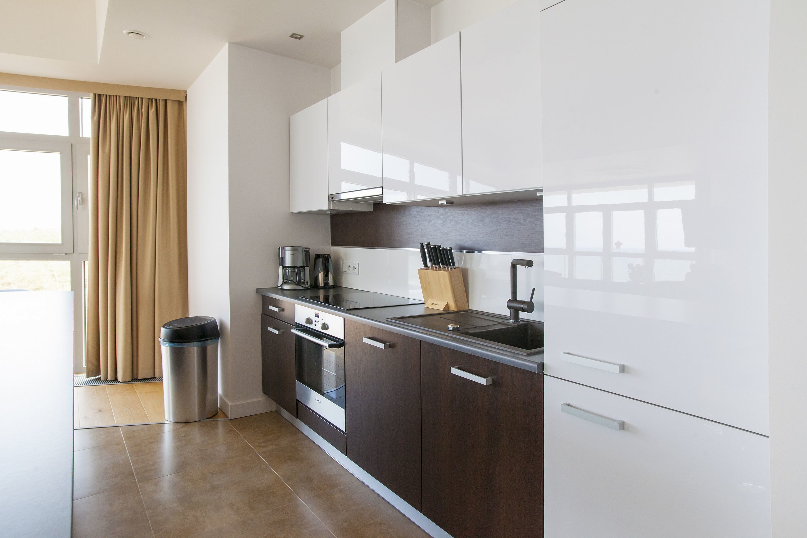 A modern kitchen with dark cabinetry, a stainless steel range, and a black sink.