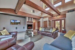 A spacious living room with leather sofas, a glass coffee table, and a fireplace.