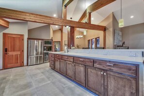 A spacious kitchen with a large island, stainless steel appliances, and wooden beams.