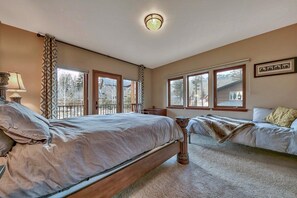 Un dormitorio con una cama grande, dos camas más pequeñas, una ventana con vistas y una lámpara en el techo.