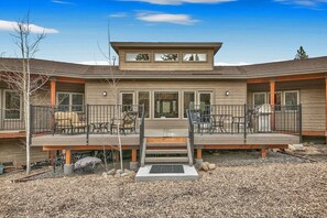 A two-story building with a covered deck, outdoor seating, and a small staircase leading to the entrance.