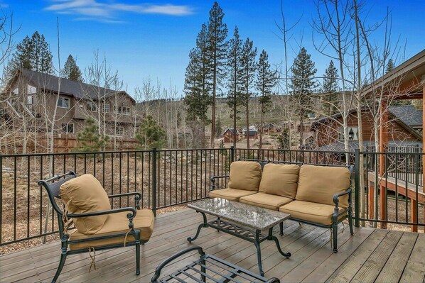A deck with a sofa and a chair, surrounded by a metal railing.