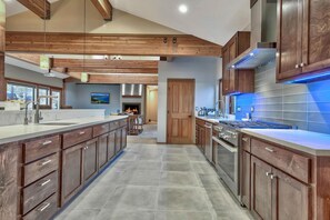 A modern kitchen with wooden cabinets, a large island, stainless steel appliances, and a view to the dining area.