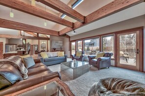 A spacious living room with a high ceiling, large windows, and a view of the outdoors.