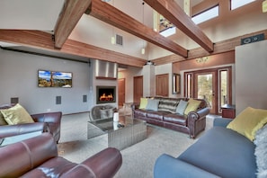 A spacious living room with leather sofas, a glass coffee table, and a fireplace.