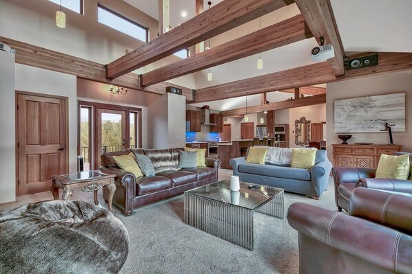 A spacious living area with a high ceiling, wooden beams, and a view to the outside.
