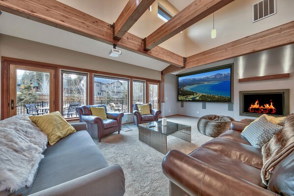 A spacious living room with leather sofas, a glass coffee table, and large windows offering a view of the outdoors.