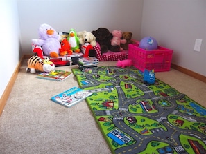 A carpeted play area with a toy train set, plush toys, and children's books.