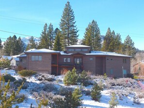 A two-story house with a front porch, surrounded by snow-covered ground and trees.