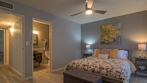 A bedroom with a bed, bedside tables, a ceiling fan, and a bathroom visible through an open door. - Amazing 2Bd/2Ba Scottsdale Condo directly across street from Fashion Square  (Scottsdale)