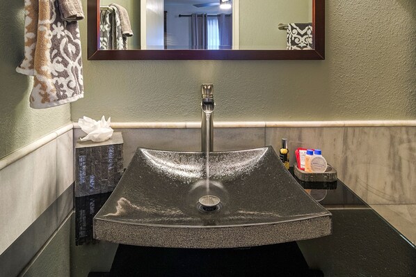 A bathroom with a large, rectangular sink, a mirror above it, and a towel rack with patterned towels.