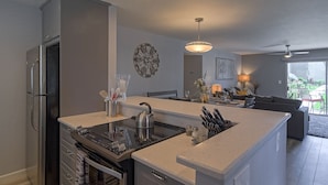 A modern kitchen with a central island, built-in appliances, and a dining area with a sofa and table. - Amazing 2Bd/2Ba Scottsdale Condo directly across street from Fashion Square  (Scottsdale)