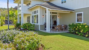 A two-story house with a covered patio, surrounded by well-maintained gardens and a lawn. - Aloha Condos, Na Hale O Keauhou, Townhome D-6, Ocean View, AC (Kailua Kona)