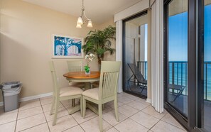 Enjoy meals in the dining area with a round table and four chairs, surrounded by a potted plant and a beautiful ocean view.
