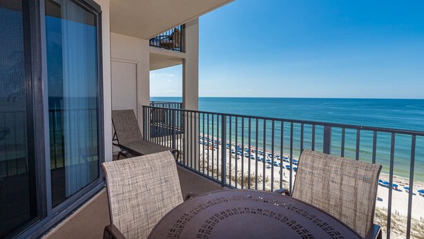 A balcony with a view of the beach and ocean. There are two chairs and a table. - Pure Beachfront Joy Phoenix X 1102 (Orange Beach)
